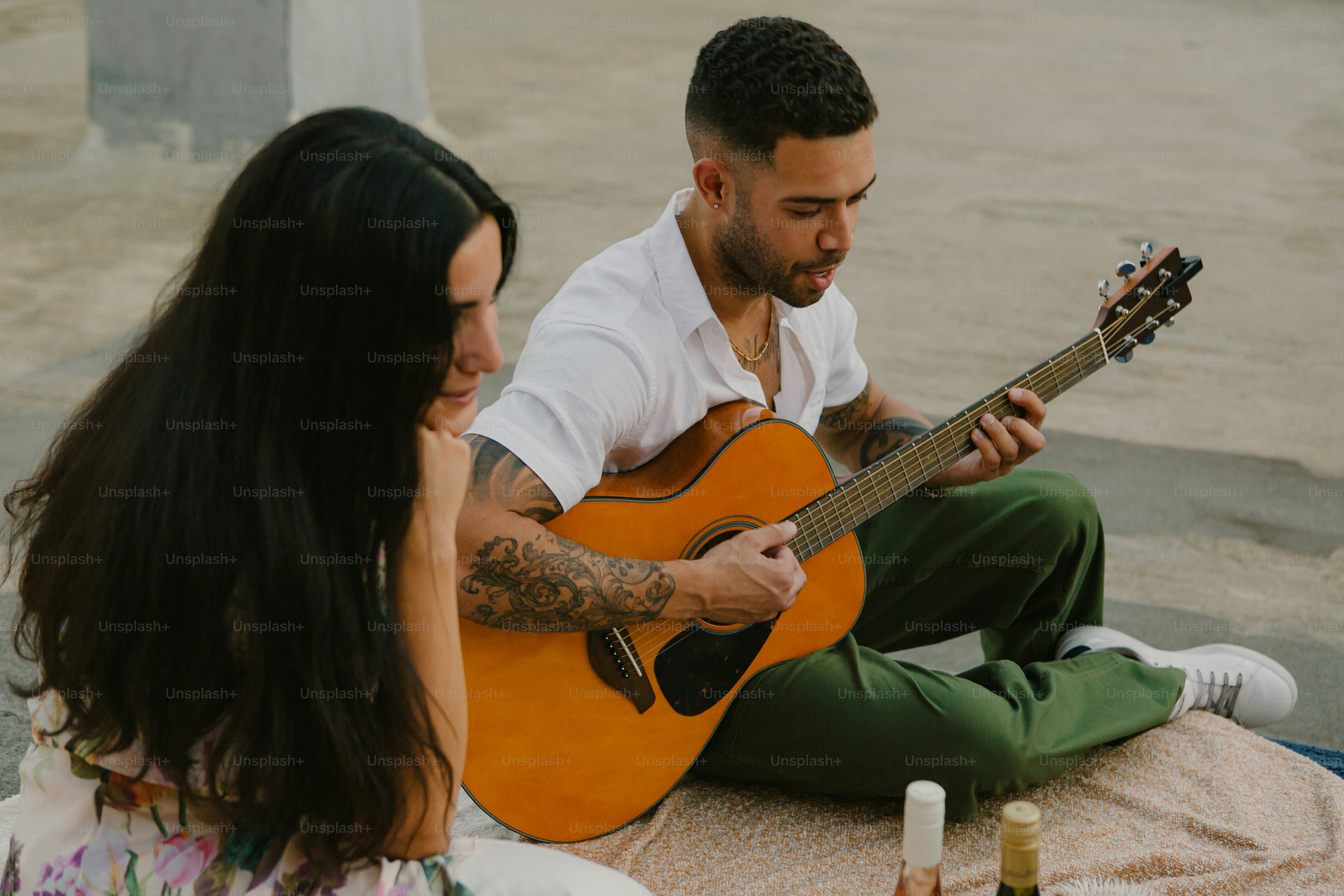 Un homme et une femme assis par terre jouant de la guitare