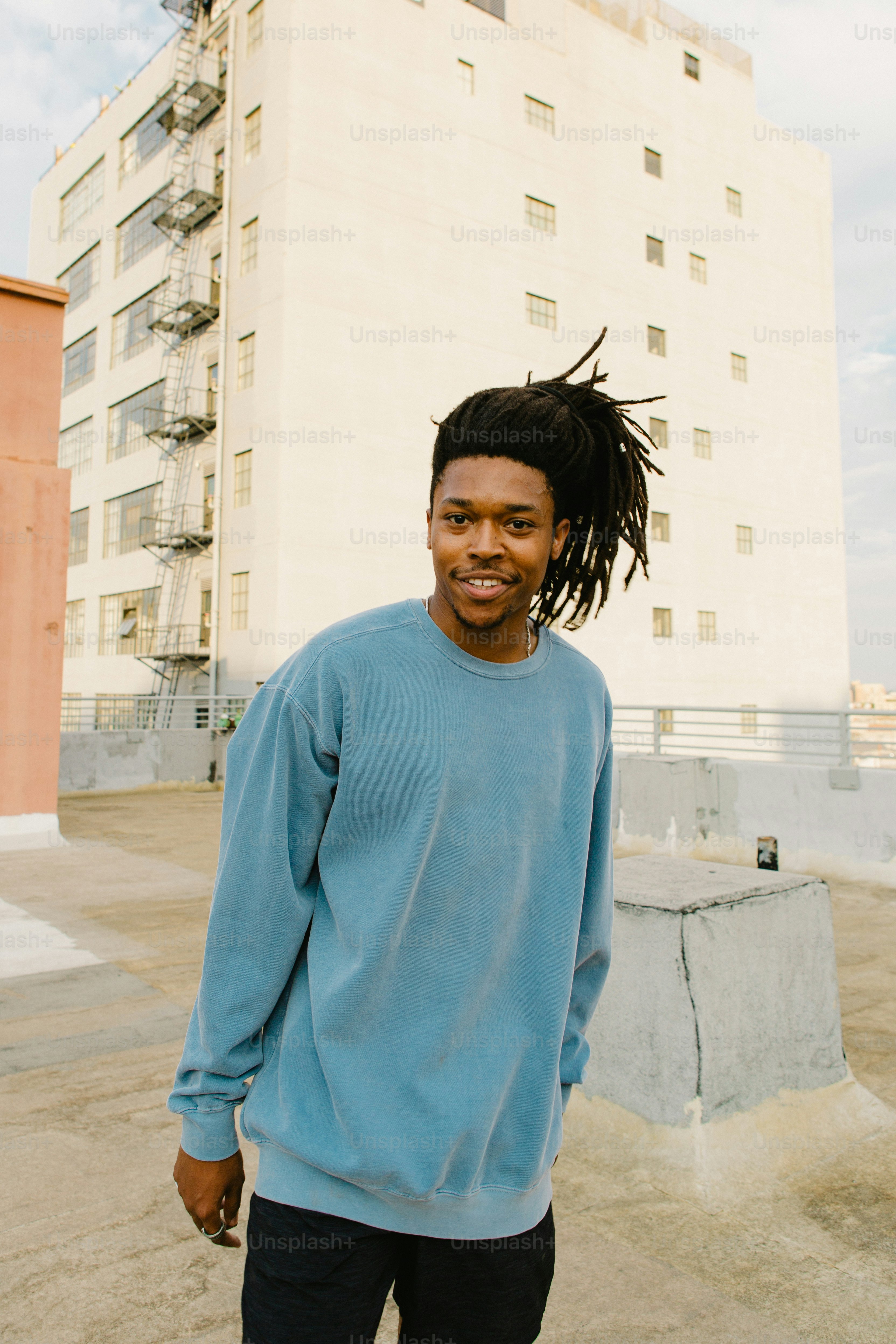 Un uomo con i dreadlocks in piedi di fronte a un edificio