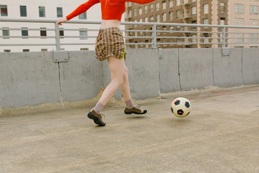 a woman kicking a soccer ball on a roof