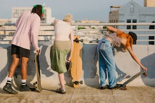 three people with skateboards leaning against a wall