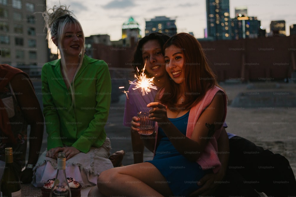 a group of women sitting next to each other holding sparklers
