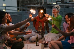 a group of people sitting around a table holding sparklers