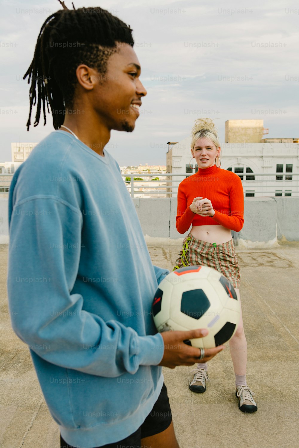 Un hombre sosteniendo un balón de fútbol junto a una mujer