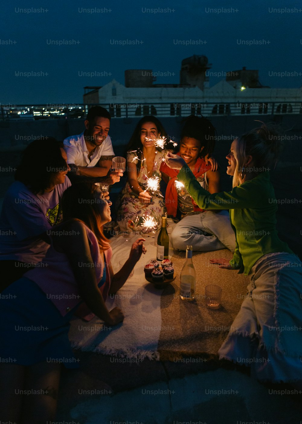 a group of people sitting around a table holding sparklers