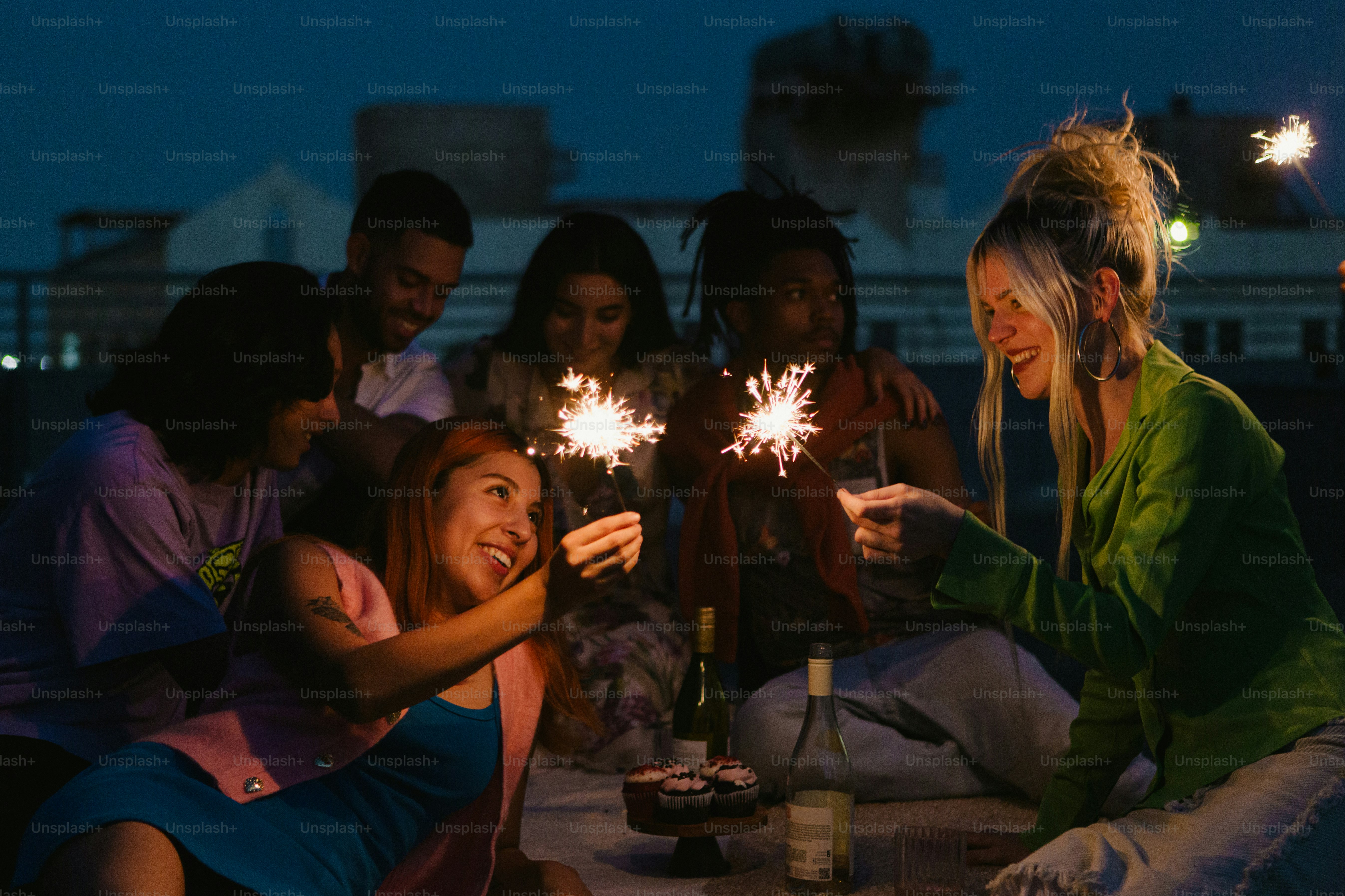 a group of people sitting around a table holding sparklers