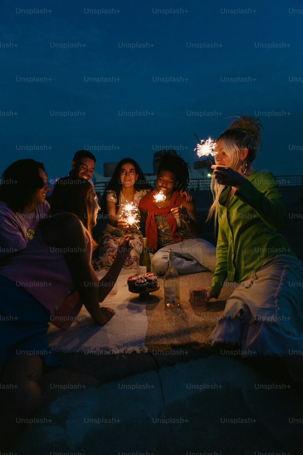 Un grupo de personas sentadas alrededor de una mesa sosteniendo bengalas