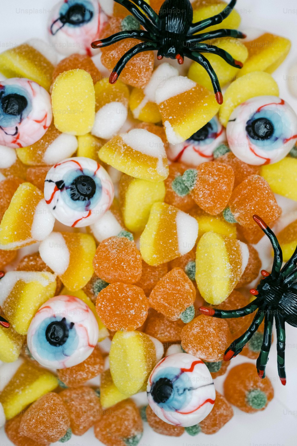 Un plato blanco cubierto con caramelos de Halloween y una araña