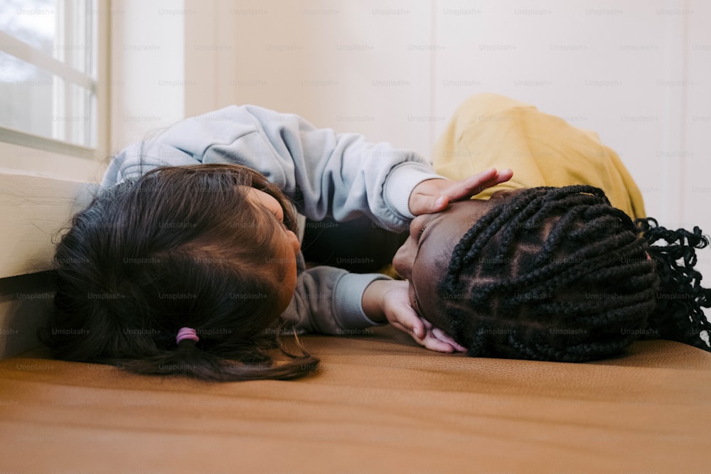 a little girl laying on the floor with her head on a little girl's