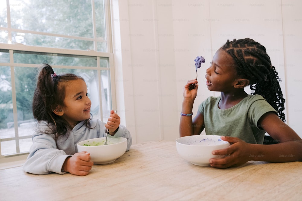 two little girls sitting at a table eating food