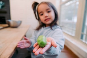 a little girl holding a green apple in her hand
