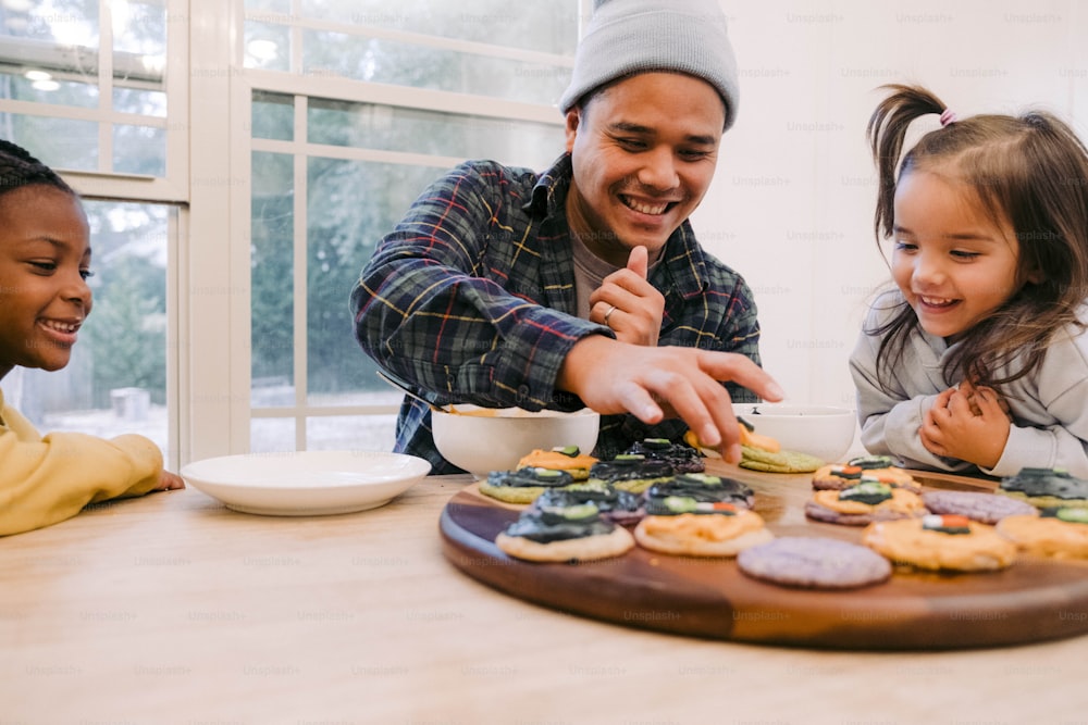Um homem e duas meninas estão fazendo biscoitos