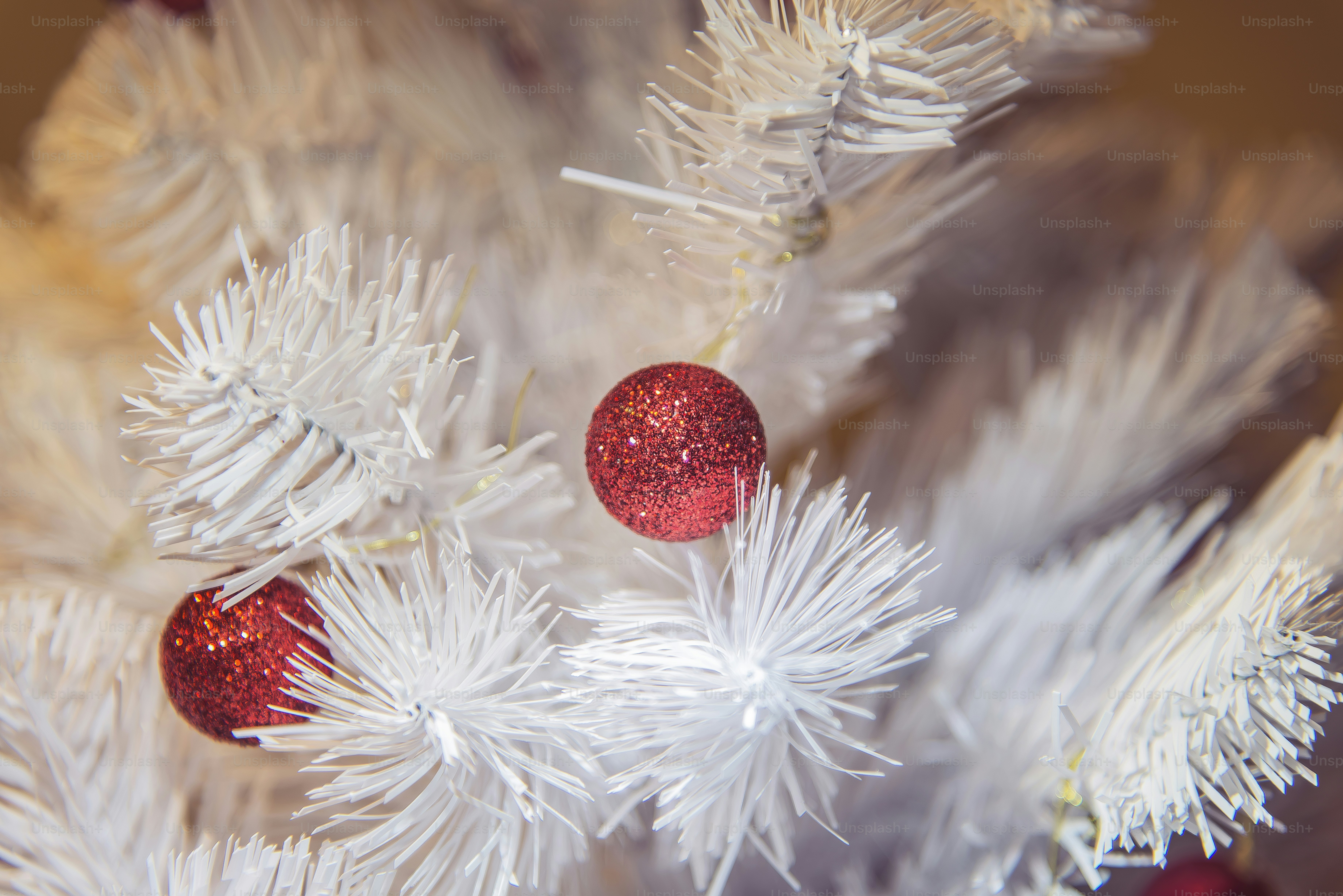 a close up of a white christmas tree with red ornaments