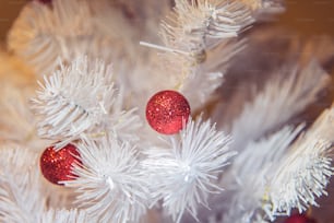 a close up of a white christmas tree with red ornaments