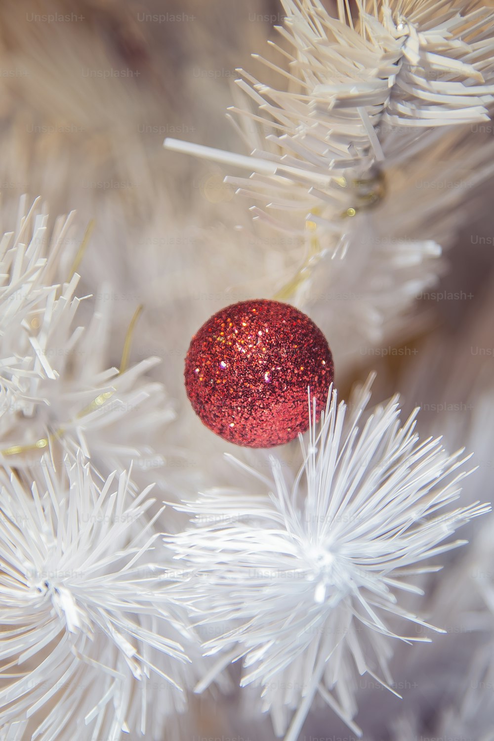 a red ornament hanging from a white christmas tree