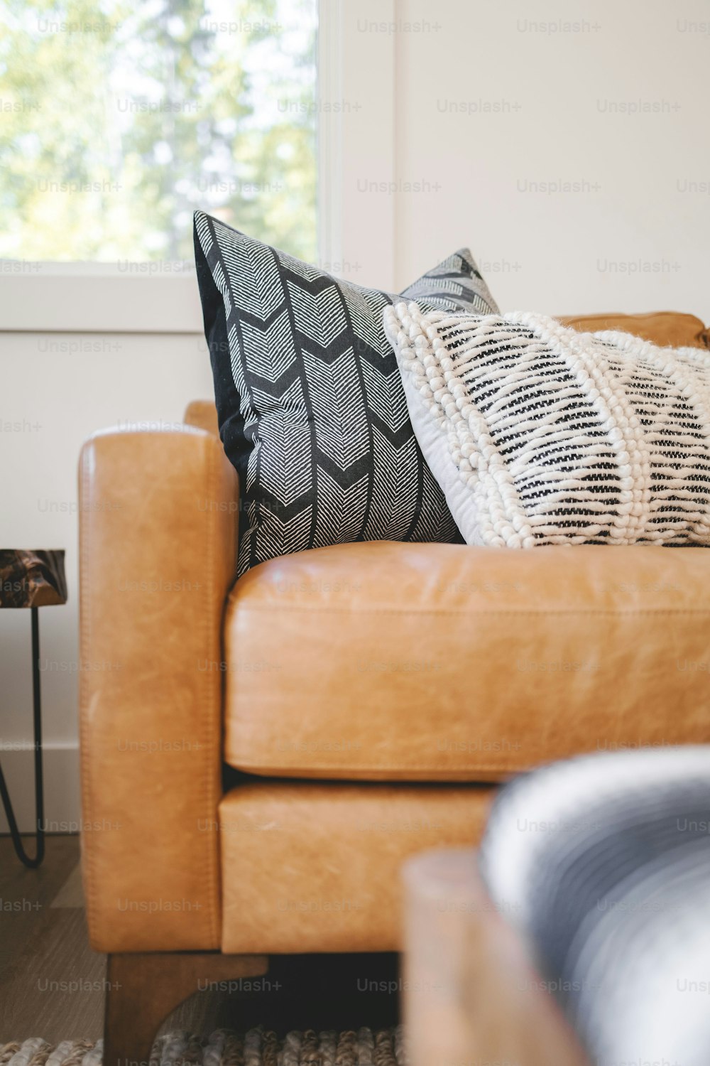 a brown leather couch with a black and white pillow