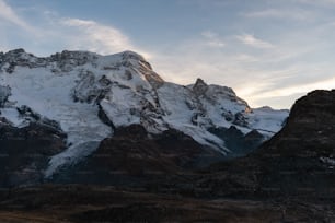 a large mountain covered in snow under a cloudy sky