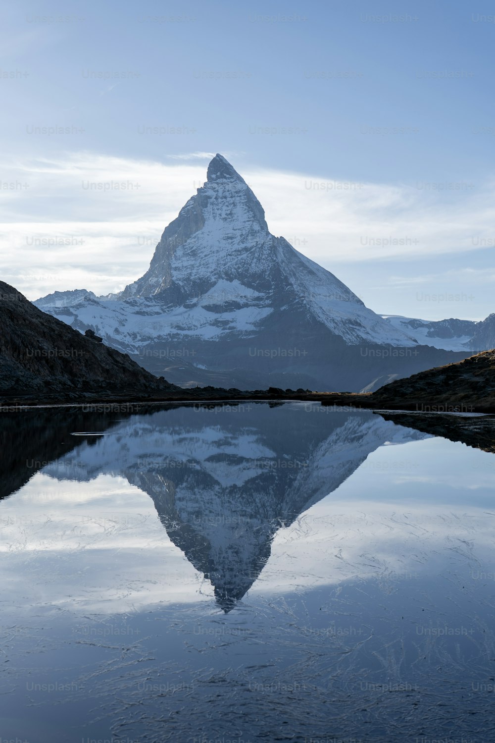 uma montanha é refletida na água parada de um lago