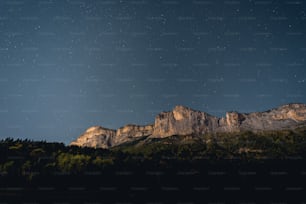 the night sky with stars above a mountain range