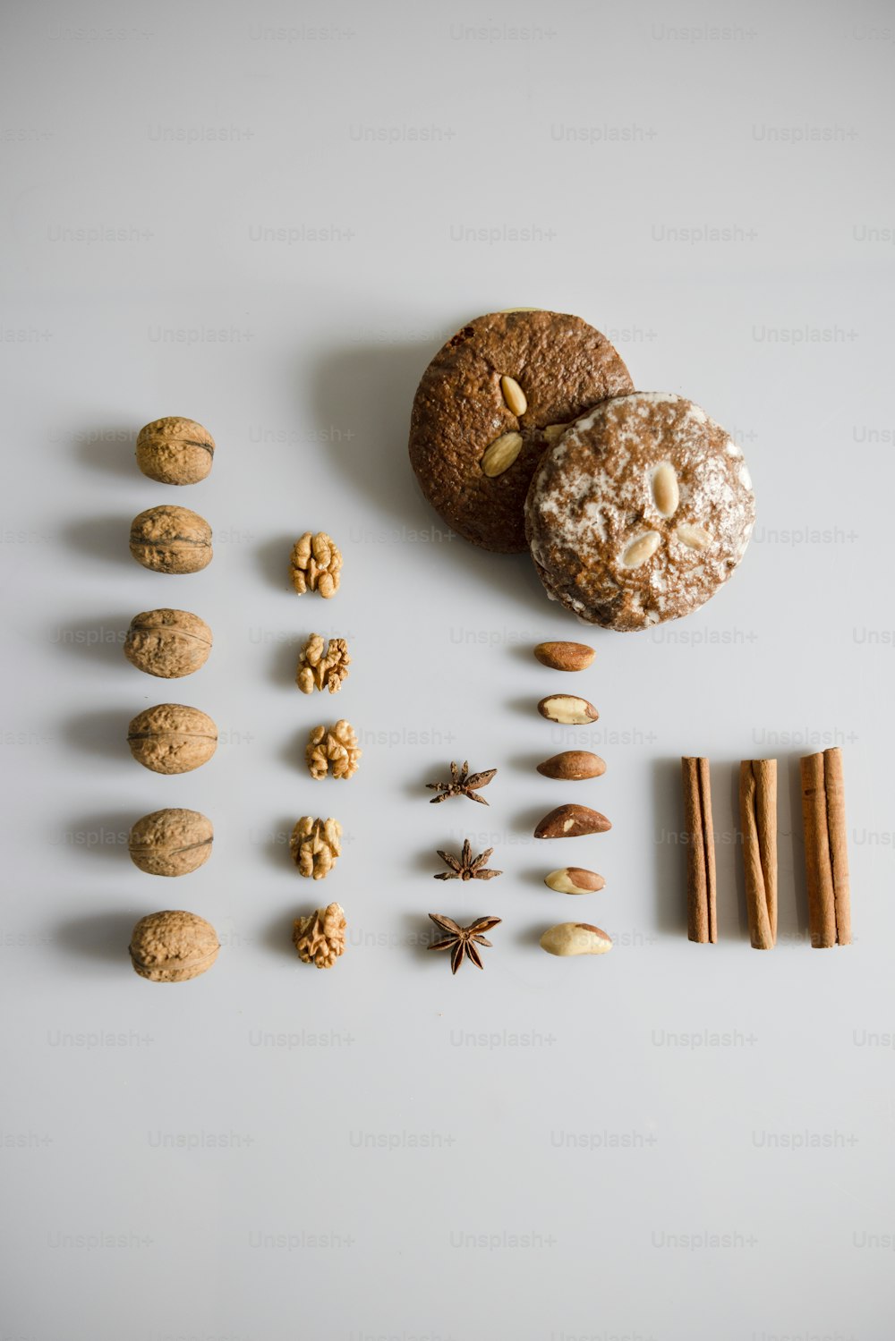 galletas, ramas de canela y nueces dispuestas sobre una superficie blanca