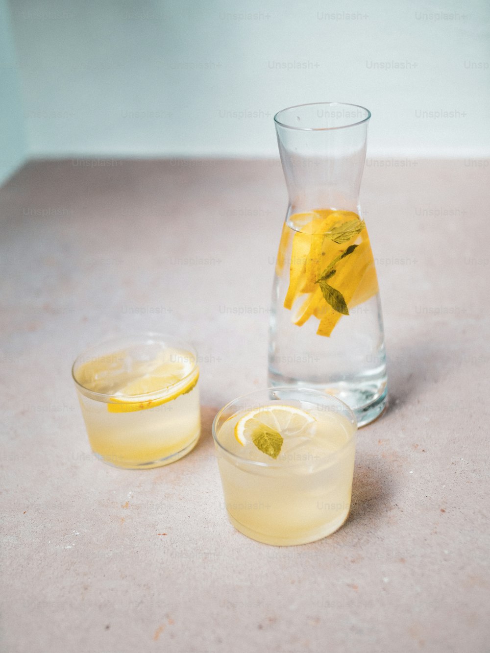 a pitcher of lemonade next to a glass of lemonade