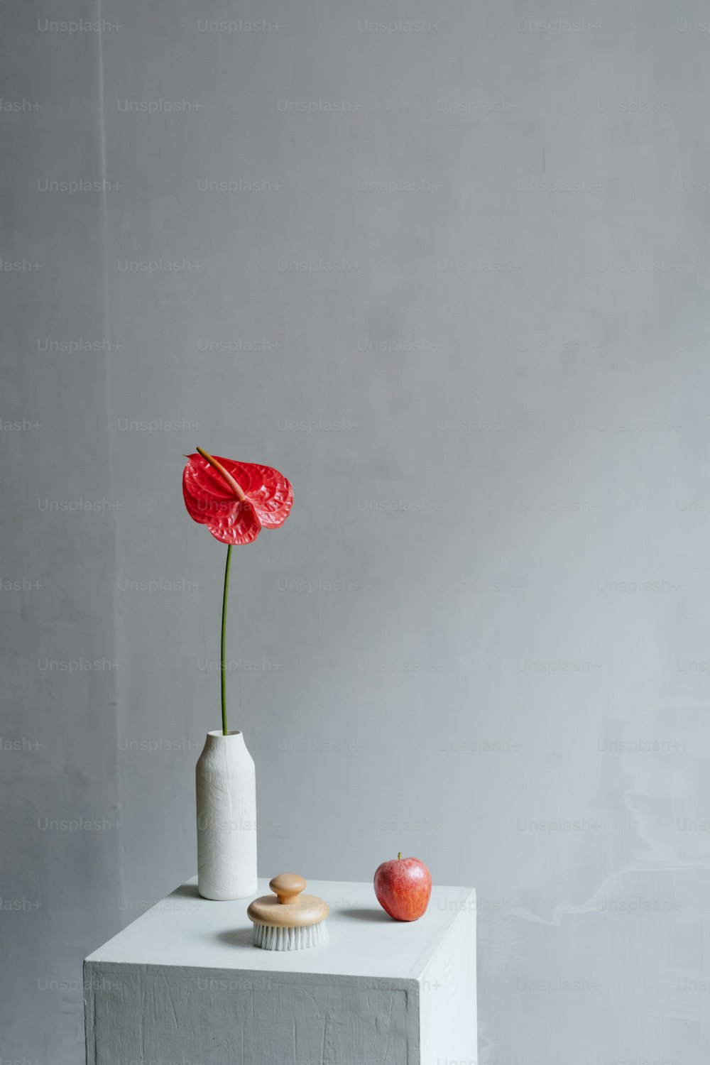 eine weiße Vase mit einer roten Blume darin