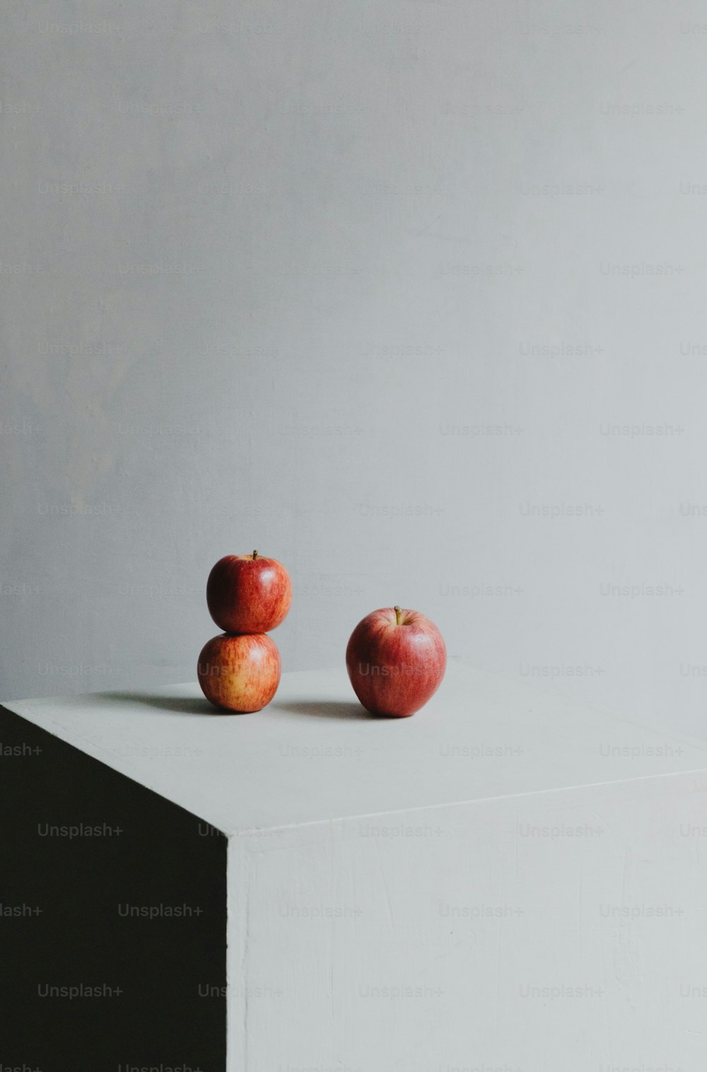 duas maçãs sentadas em cima de uma superfície branca