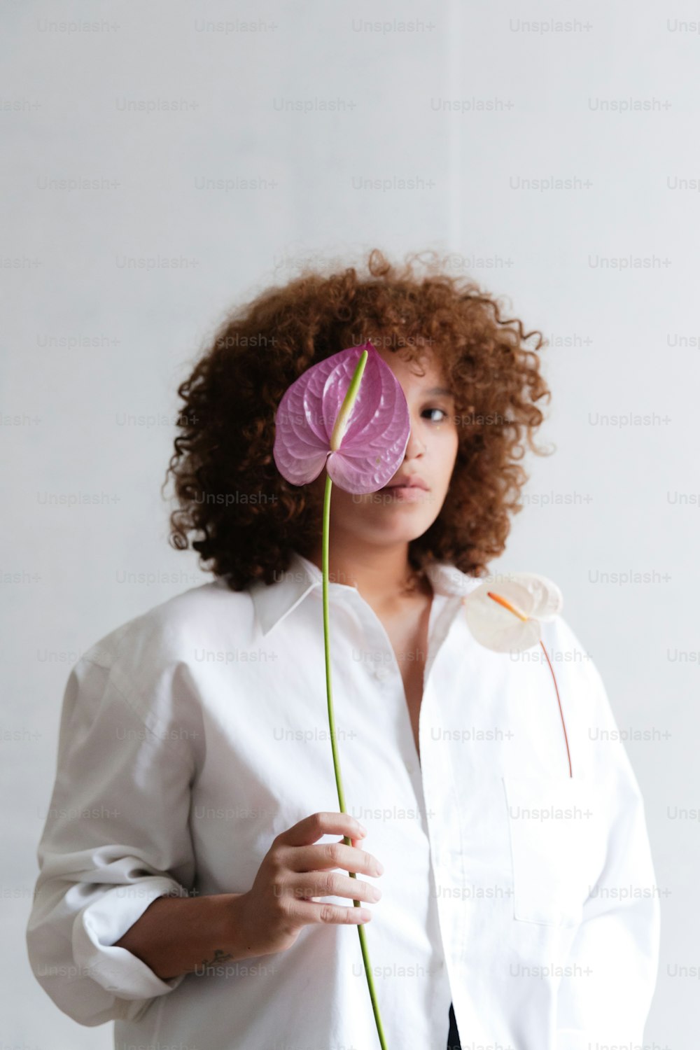 a woman with curly hair holding a flower