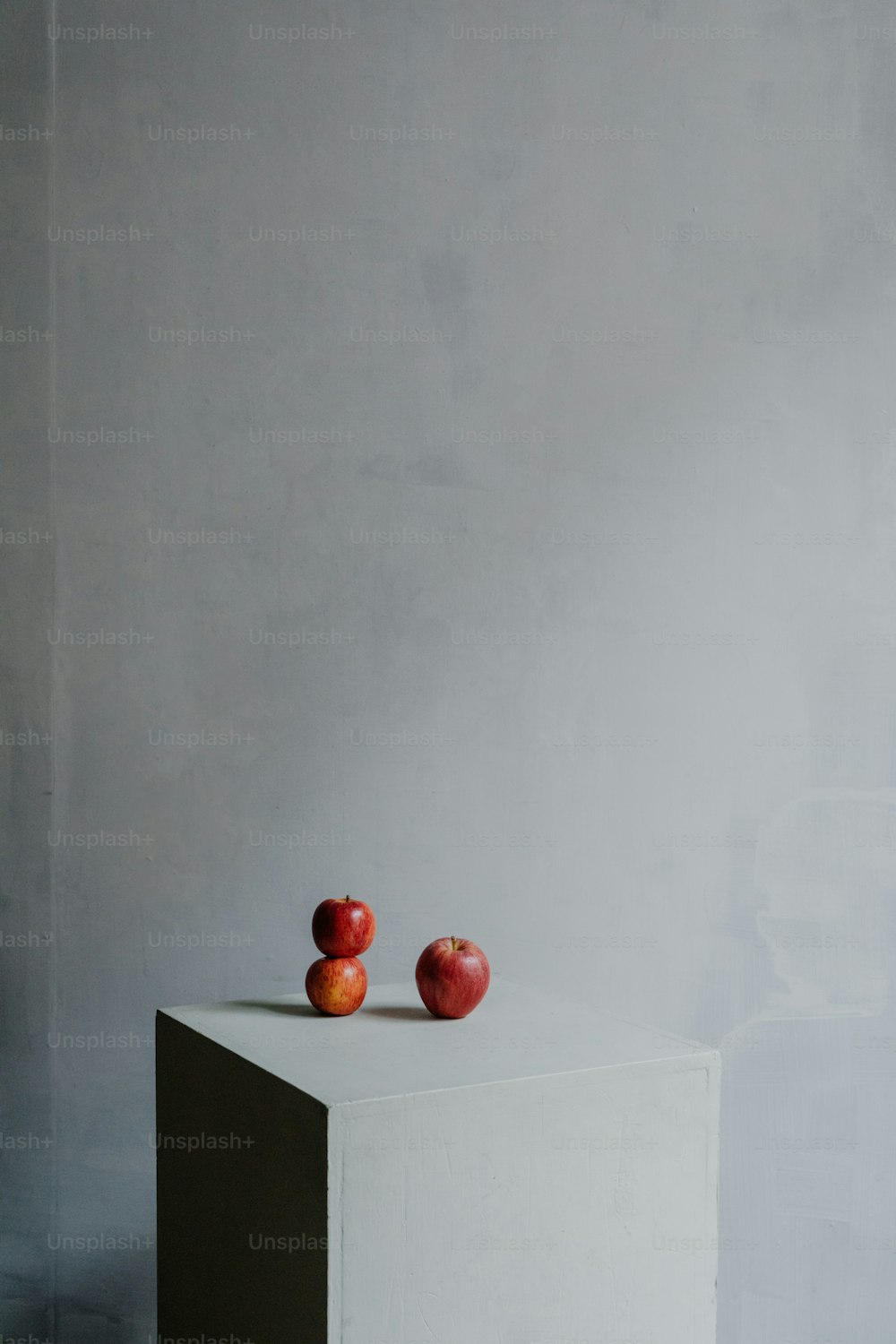 two apples sitting on top of a white block