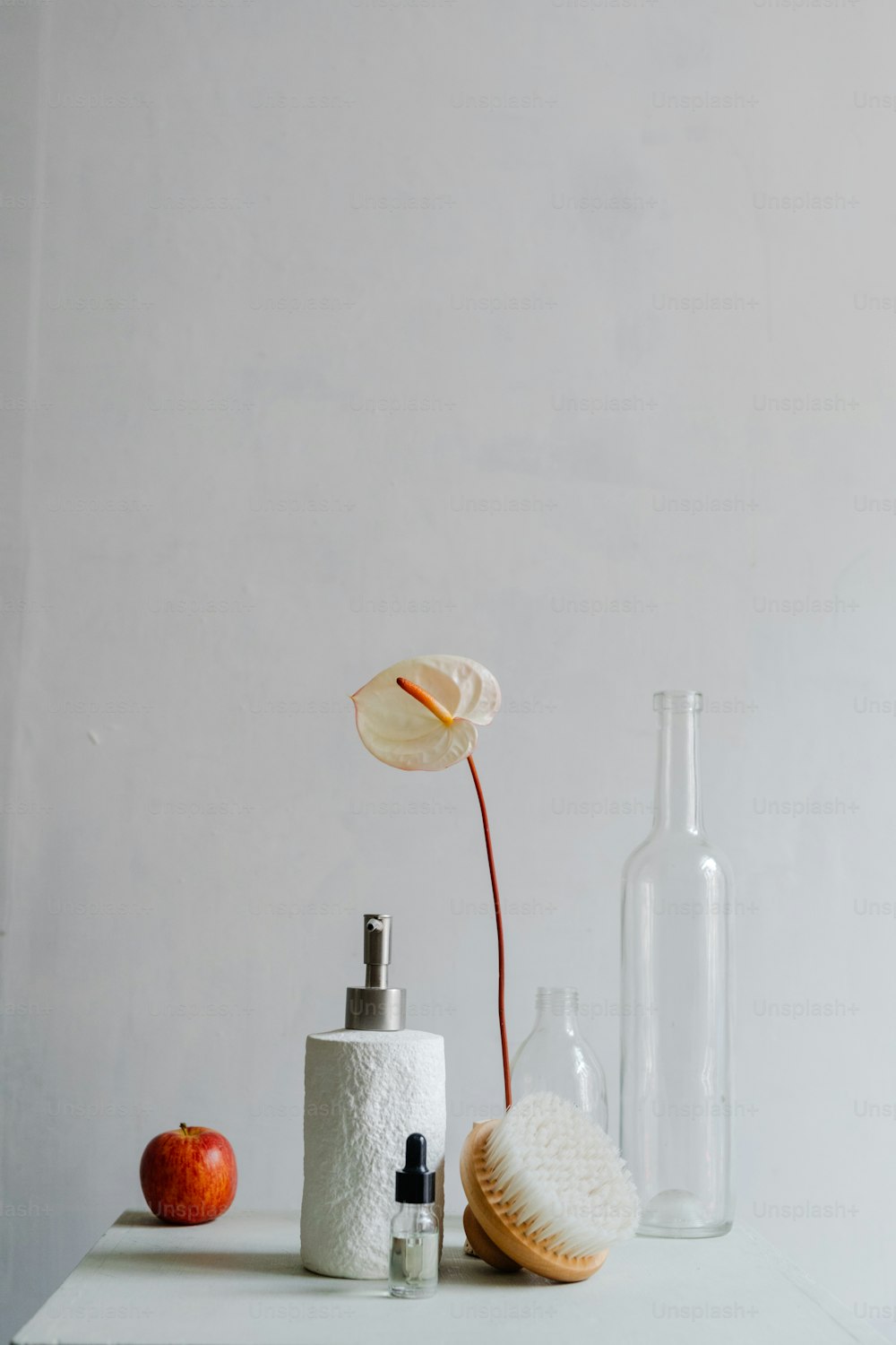 a white table topped with a soap dispenser and an apple
