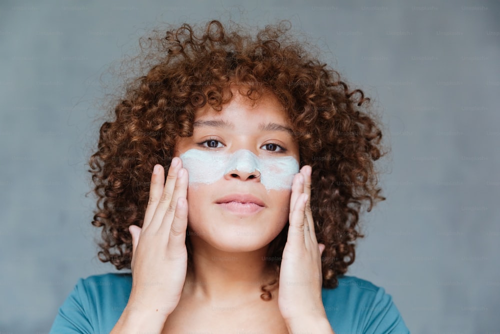 a woman holding her hands to her face with a lot of cream on her face
