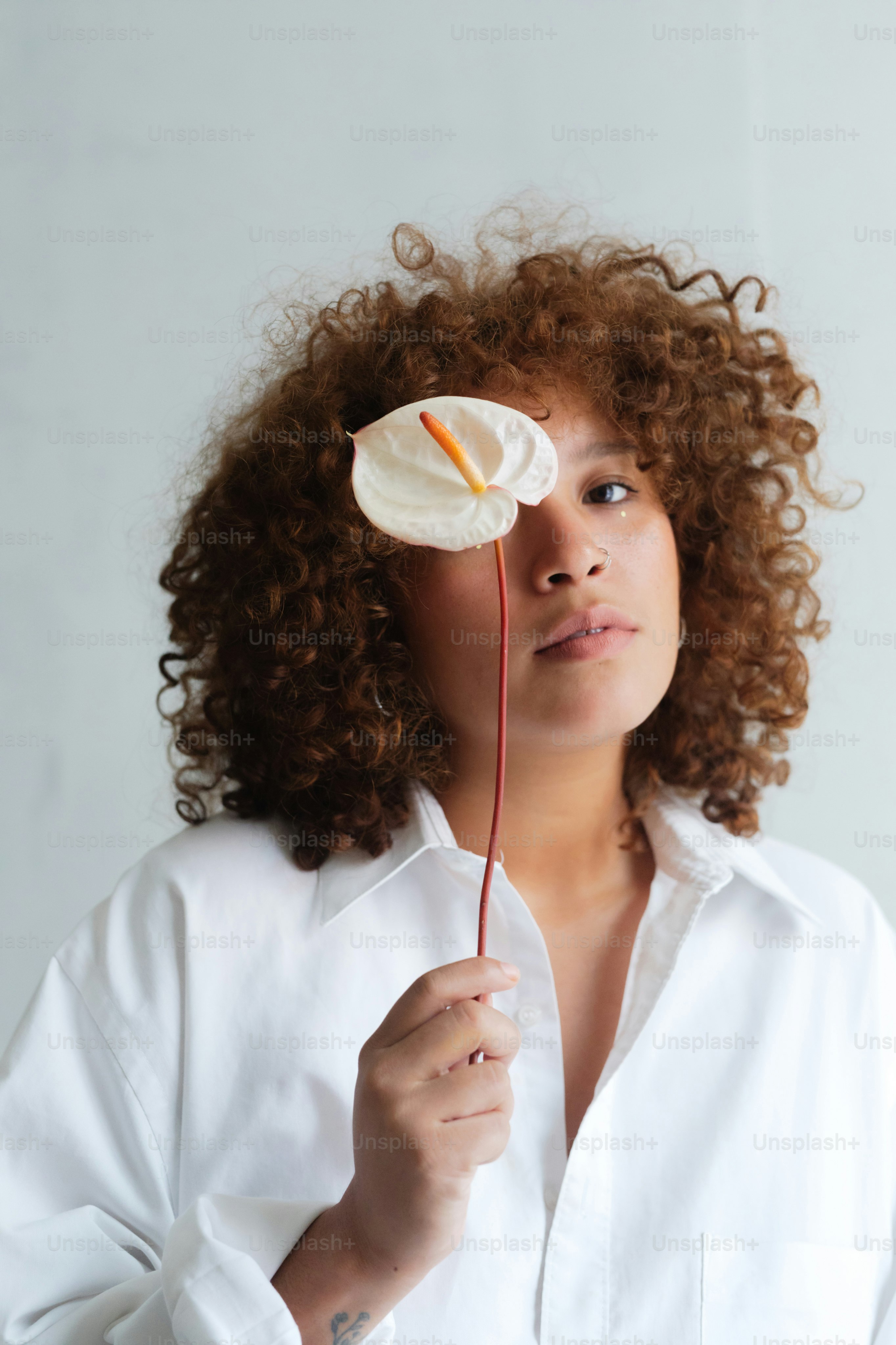 Una mujer con cabello rizado sosteniendo una flor