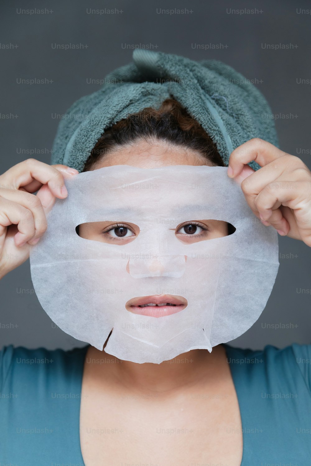 Una mujer con una hoja de papel cubriendo su rostro