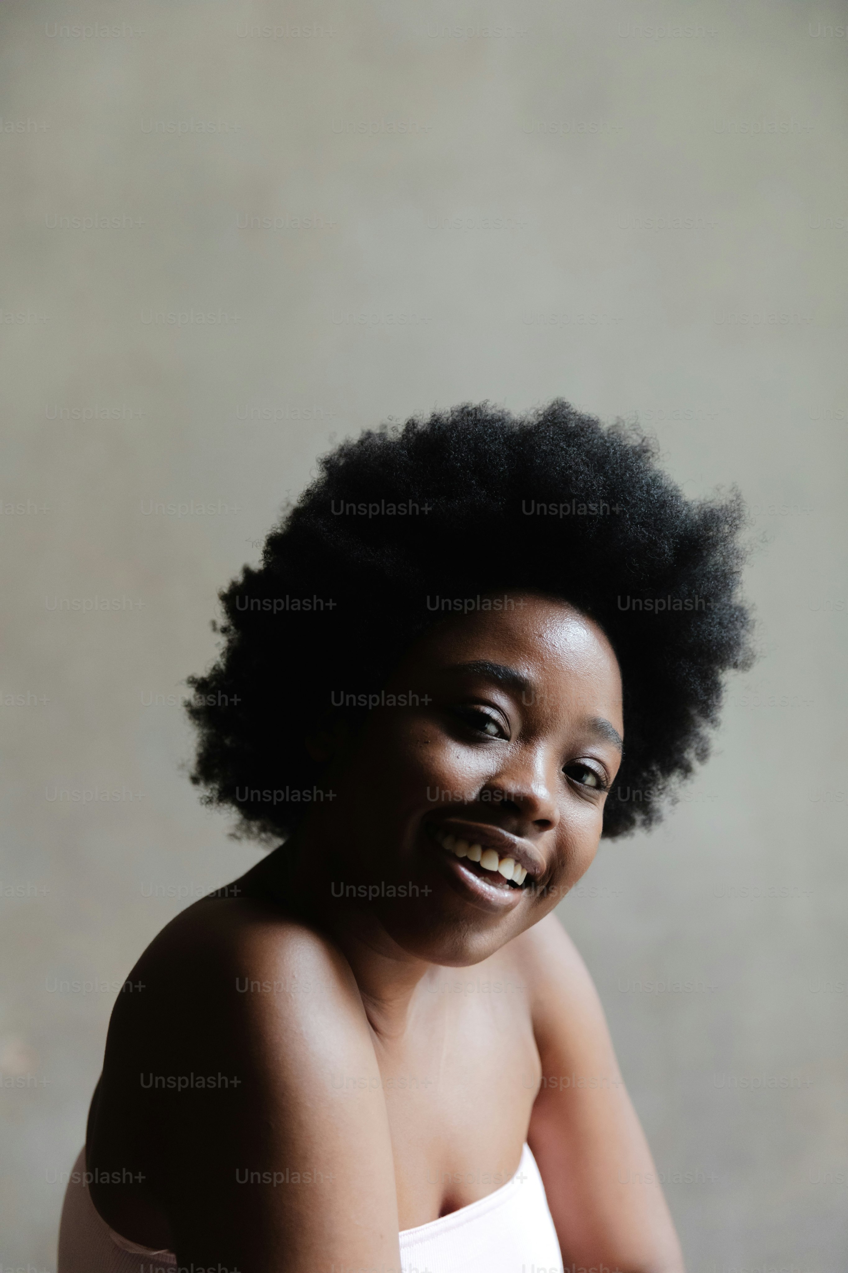 Una donna con un afro sorride per la macchina fotografica