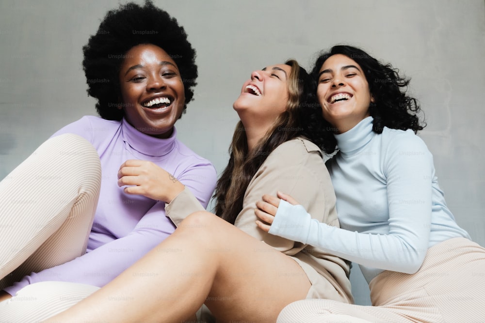 Tres mujeres riendo mientras están sentadas en el suelo