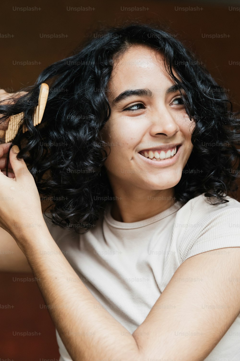 a woman is smiling and holding a hair brush