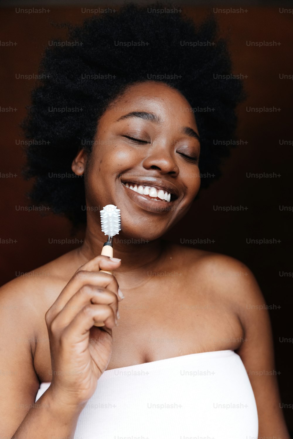 a woman smiles while holding a toothbrush