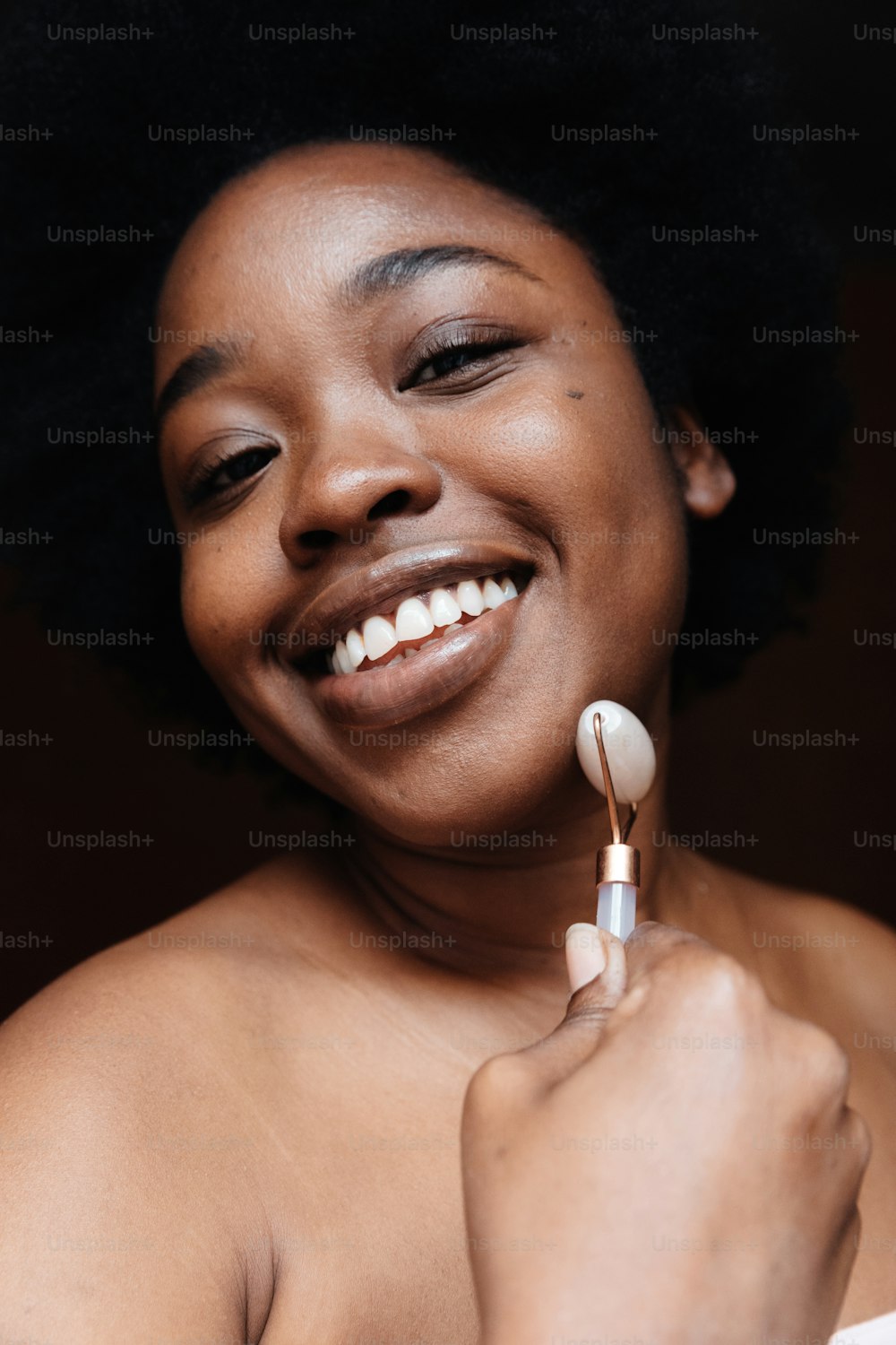 Une femme sourit tout en tenant une brosse à dents
