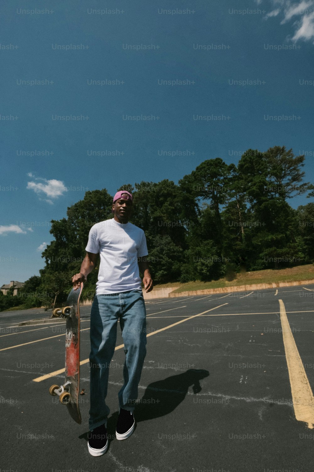 Ein Mann, der ein Skateboard auf einem Parkplatz hält