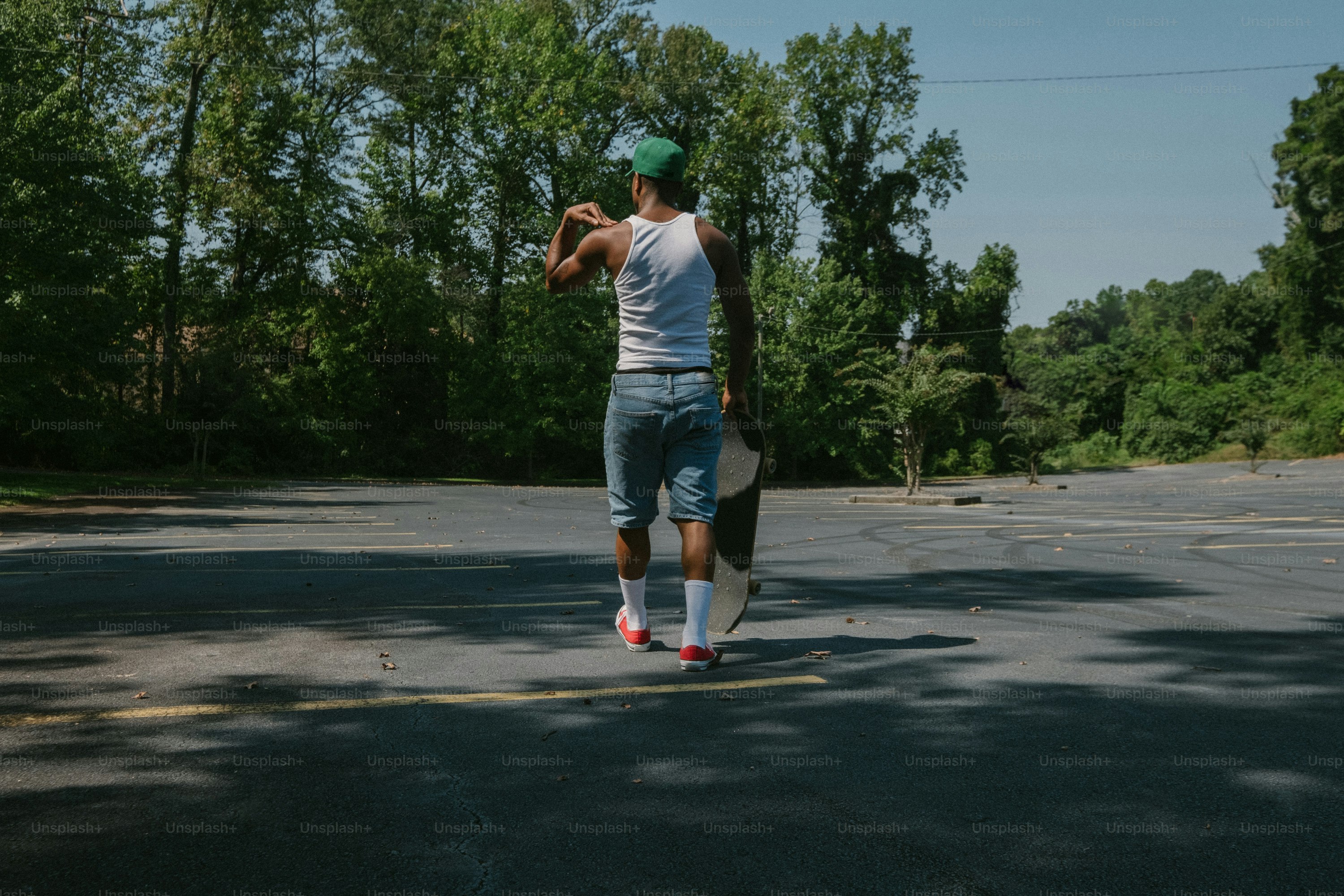 a man walking across a street holding a skateboard