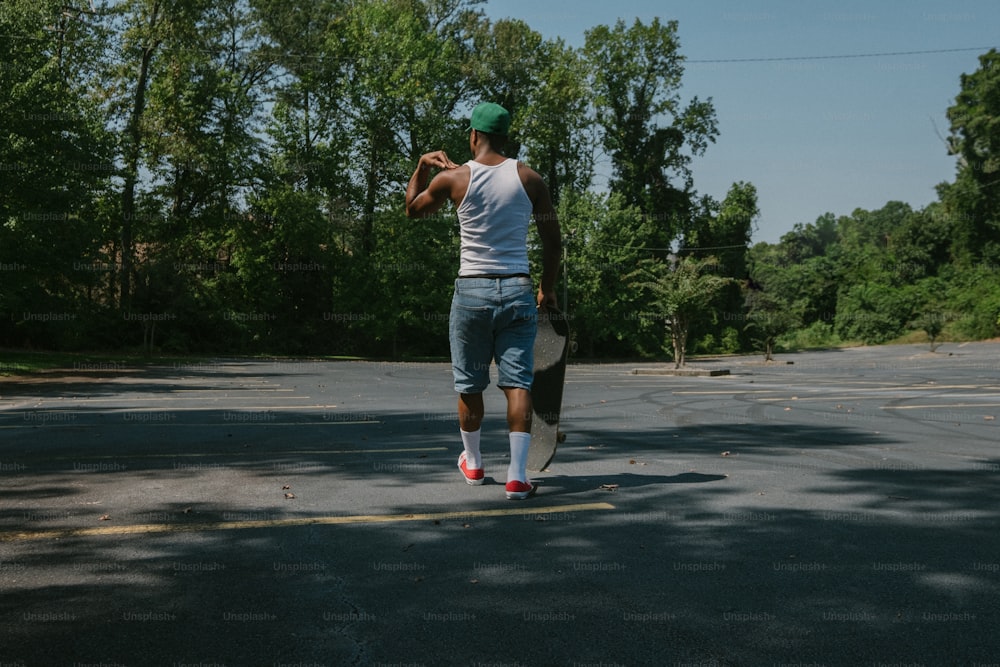 Un uomo che cammina attraverso una strada tenendo uno skateboard