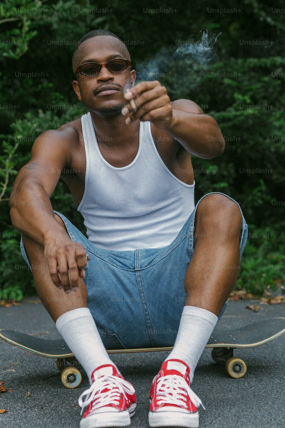 Ein Mann, der auf einem Skateboard sitzt und eine Zigarette raucht