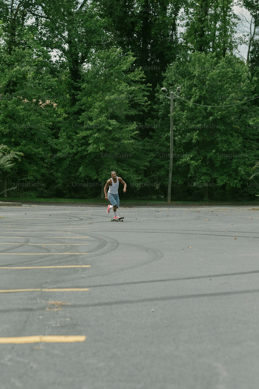 주차장을 가로질러 스케이트보드를 타는 남자