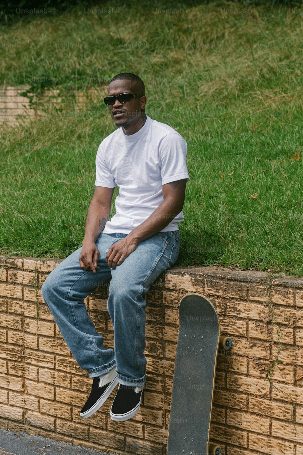 a man sitting on a brick wall with a skateboard