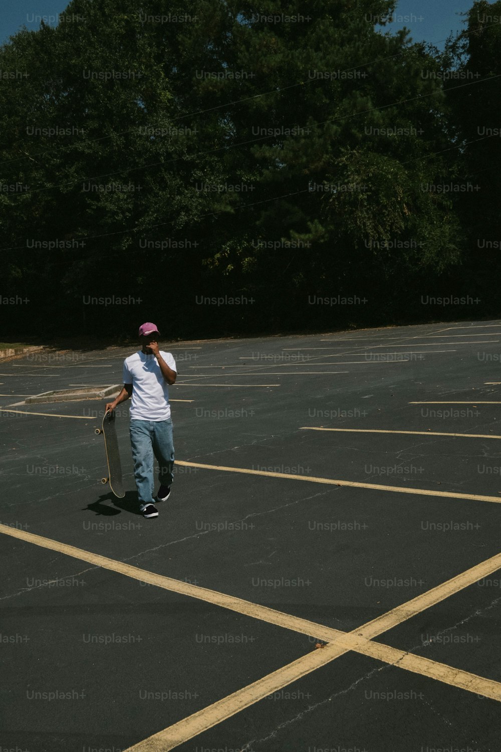 a man holding a skateboard in a parking lot