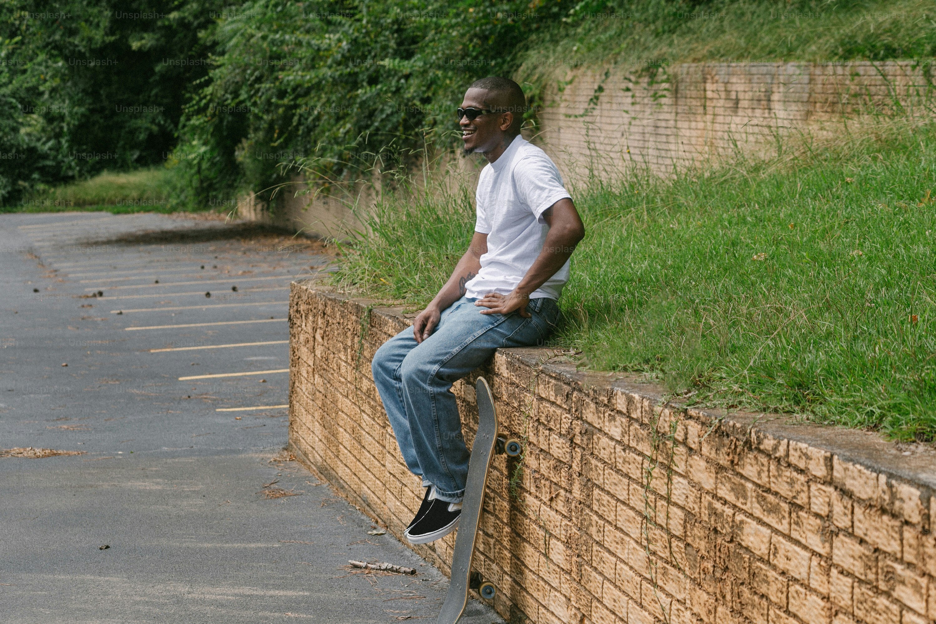 a man sitting on a brick wall with a skateboard