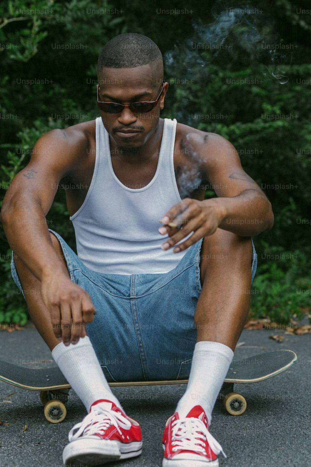 Un uomo seduto su uno skateboard che fuma una sigaretta