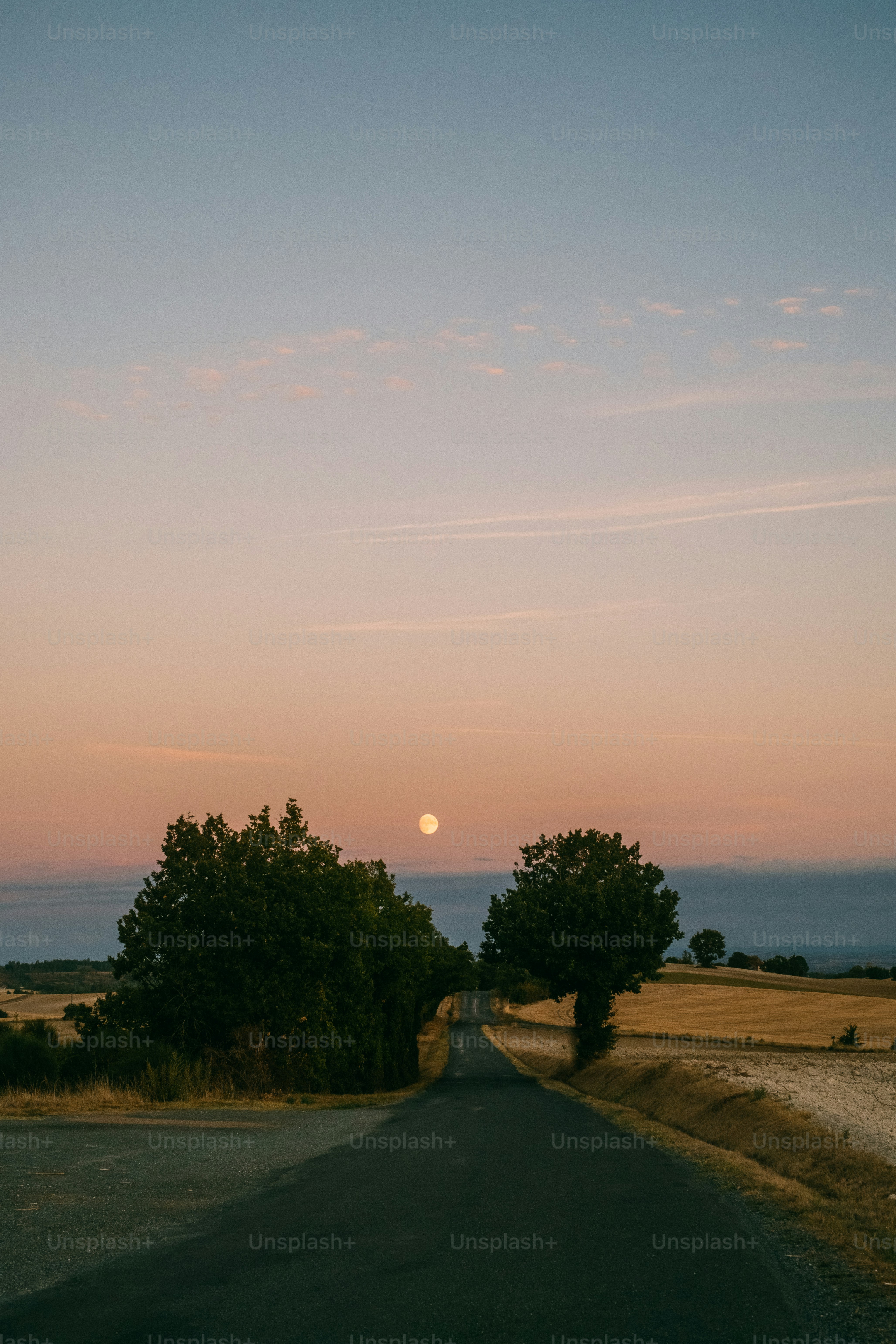 the sun is setting over a rural road