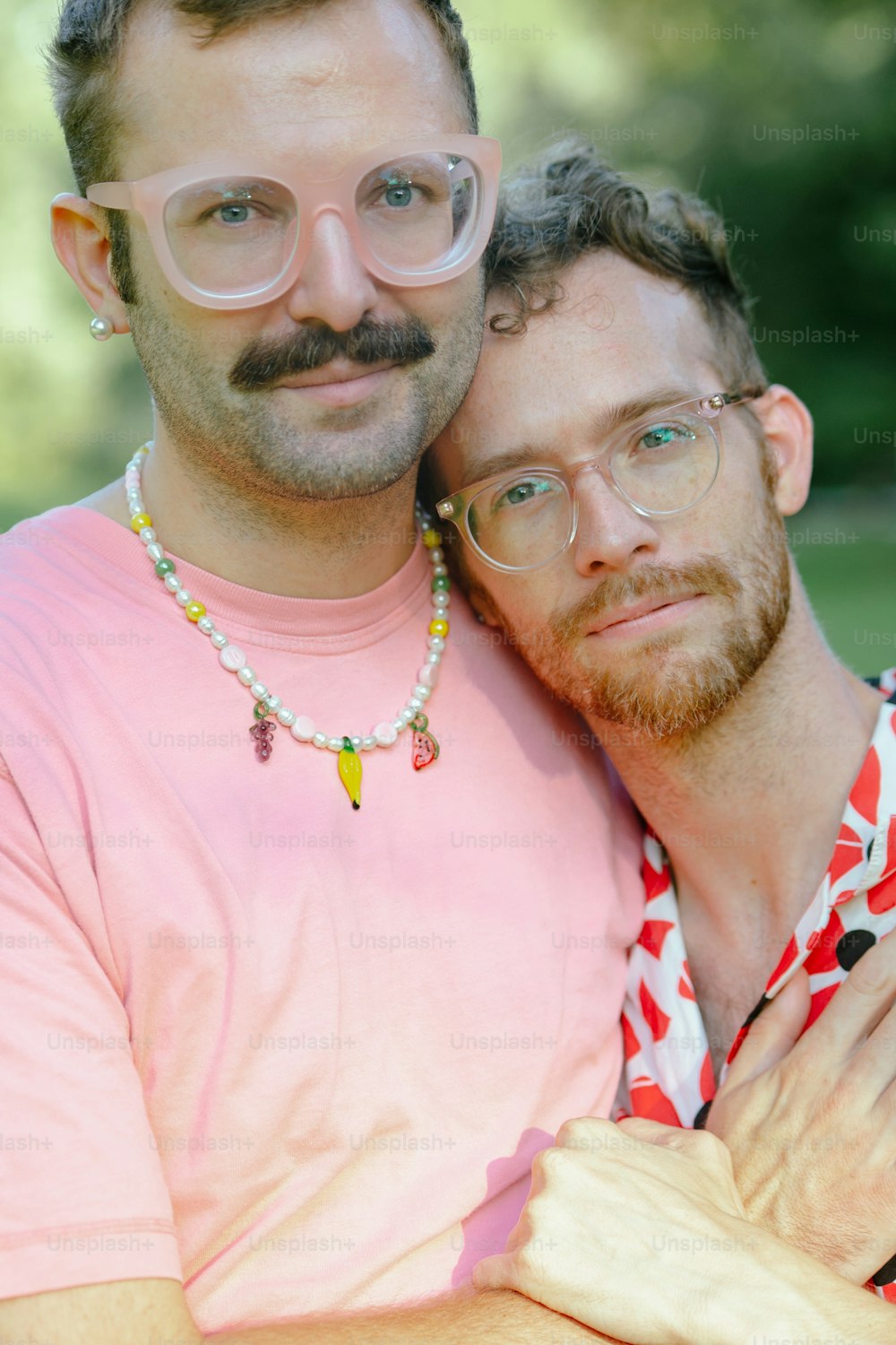 Ein Mann mit Schnurrbart und Brille, der einen anderen Mann umarmt