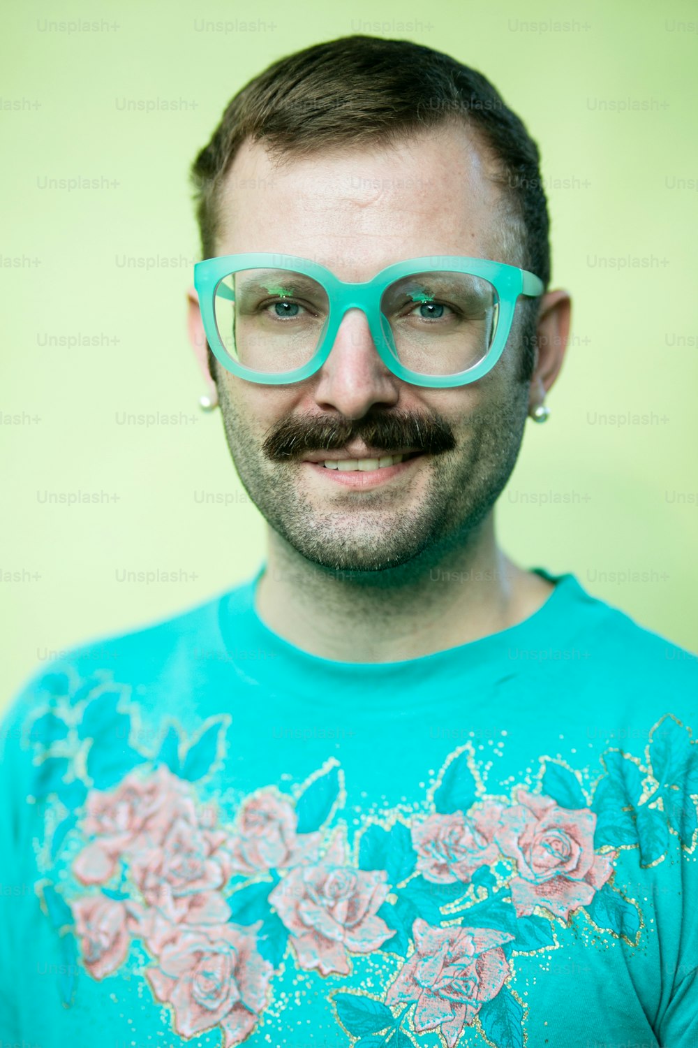 Un uomo con occhiali e baffi che indossa una maglietta