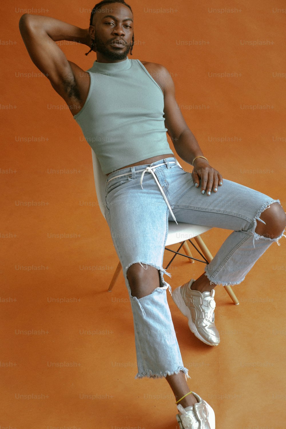 a man sitting on a chair wearing ripped jeans